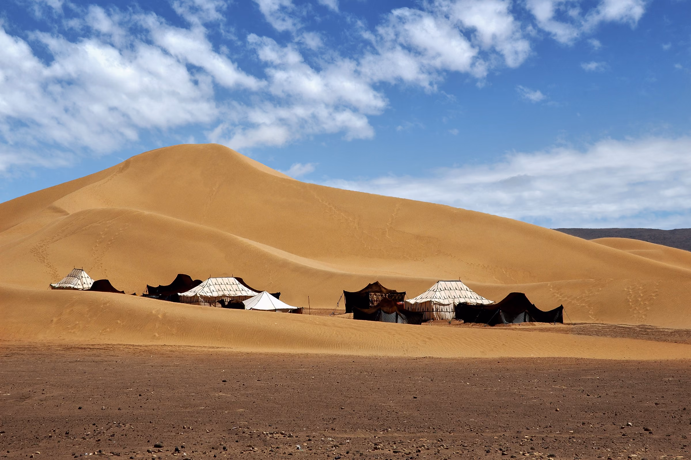 Jaimas negras de un campamento nómada al pie de una gran duna cerca de M'hamid